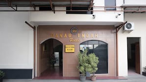 La entrada del Hotel Danaudi Indah, con un cartel de recepción, un árbol de Navidad y plantas en macetas.