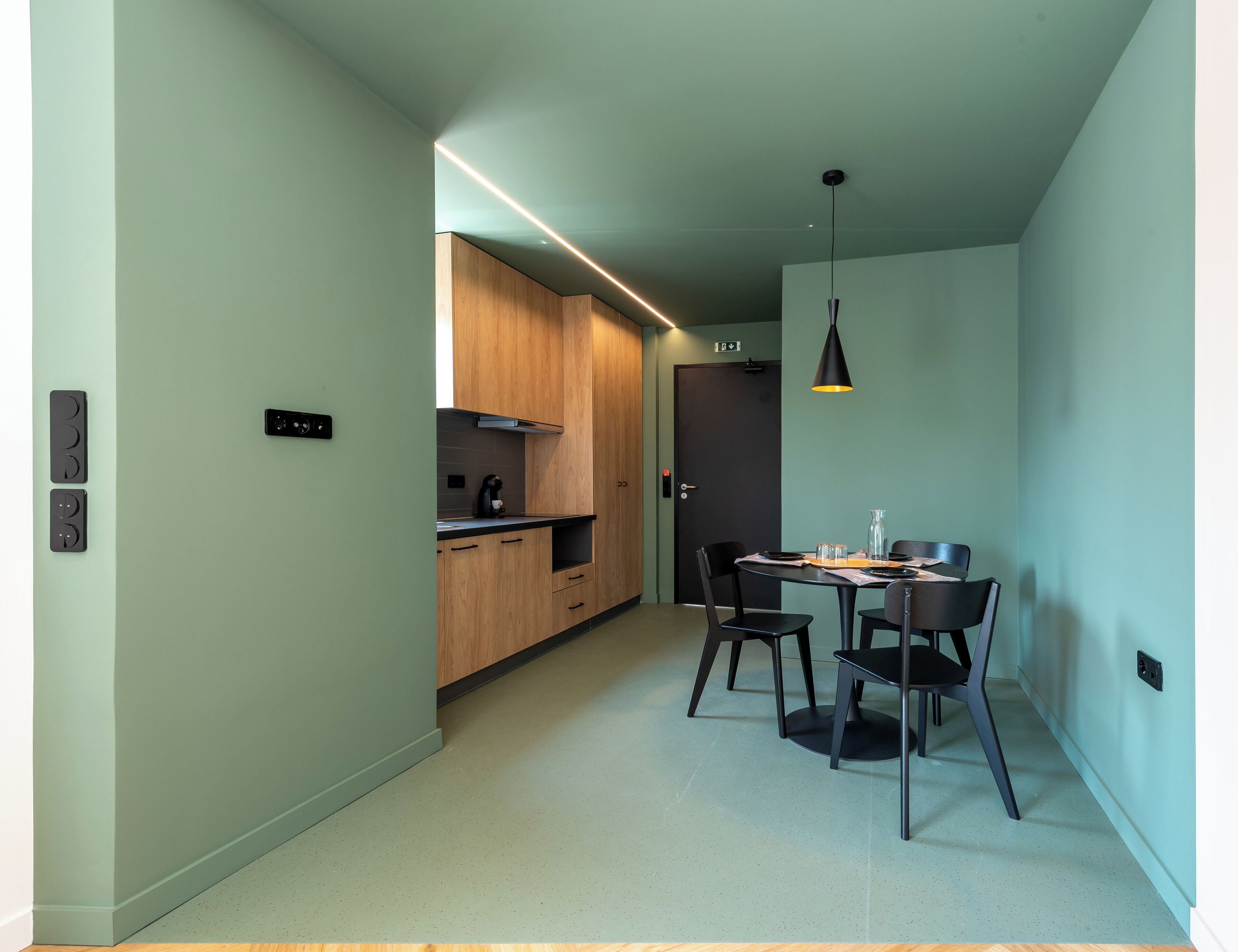 A modern kitchen with wooden cabinets, a dining table with chairs, and a pendant light.
