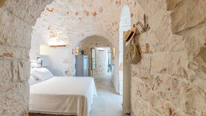 A stone-walled bedroom with a bed, a nightstand, and a hanging basket. - Villa in Ostuni with 3 bedrooms sleeps 6 (Ostuni)
