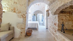 A narrow passageway with a white sofa and a wicker basket, leading to a bedroom with a bed and a dresser. - Villa in Ostuni with 3 bedrooms sleeps 6 (Ostuni)