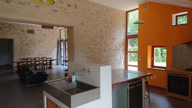 Eine moderne Küche mit einer großen Kochinsel, integriertem Backofen und einem Essbereich mit Stühlen.