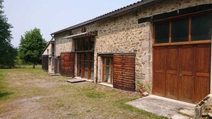 Ein rustikales Steinhaus mit Holzläden und einer großen Holztür zur Garage.