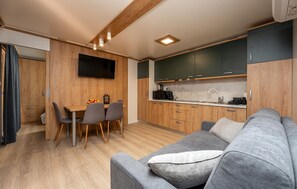 A compact kitchen with wooden cabinets, a dining area with a table and chairs, and a grey sofa with a pillow. - Stunning home in Privlaka (Privlaka)