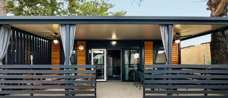 A modern building with a covered entrance, wooden walls, and a seating area with benches.