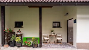 A covered outdoor area with potted plants, two wooden chairs, and a small table. - 3 bedroom lovely apartment in Lokve (Lokve)