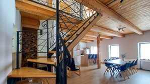 A spacious room with a wooden staircase, a dining area with blue chairs, and a kitchen in the background. - 3 bedroom lovely apartment in Lokve (Lokve)