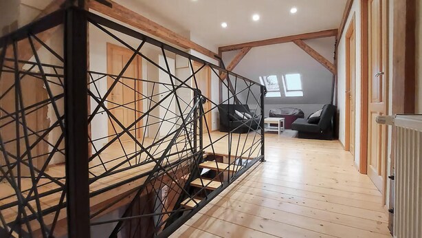 A spacious loft with a high ceiling, exposed wooden beams, and a mezzanine level with a metal railing. - 3 bedroom lovely apartment in Lokve (Lokve)