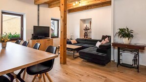 A modern living room with a wooden ceiling, a television, a sofa, a dining table with chairs, and a potted plant. - 3 bedroom lovely apartment in Lokve (Lokve)