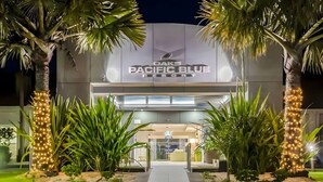 The exterior of DAKS Pacific Blue Resort with a pathway leading to the entrance, surrounded by palm trees and well-maintained landscaping. - The Oaks Pacific Blue 1 Bedroom Apartment (Salamander Bay)