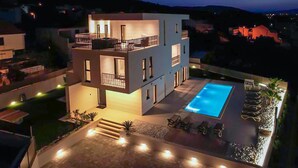 A modern two-story building with a swimming pool, outdoor seating, and a well-lit balcony. - Stunning home in Slatine (Slatine)