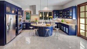 A modern kitchen with blue cabinets, a central island with stools, stainless steel appliances, and a large window providing natural light. - Secluded 4BDR Retreat w/ Pool, Hot Tub, Views | Shiloh Vista Estate by AvantStay (Santa Rosa)
