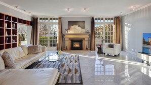 A spacious living room with a fireplace, a sofa, a coffee table, and a television. - Secluded 4BDR Retreat w/ Pool, Hot Tub, Views | Shiloh Vista Estate by AvantStay (Santa Rosa)