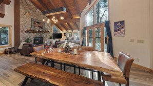 Un amplio salón con una gran mesa de madera para comer, chimenea de piedra y una pared de piedra.