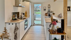 A modern kitchen with a central island, built-in appliances, and a view of the outdoors.