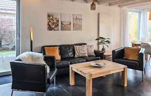 Ein modernes Wohnzimmer mit einer schwarzen Ledersofa, einem Holztisch und einem großen Fenster mit Blick ins Freie.