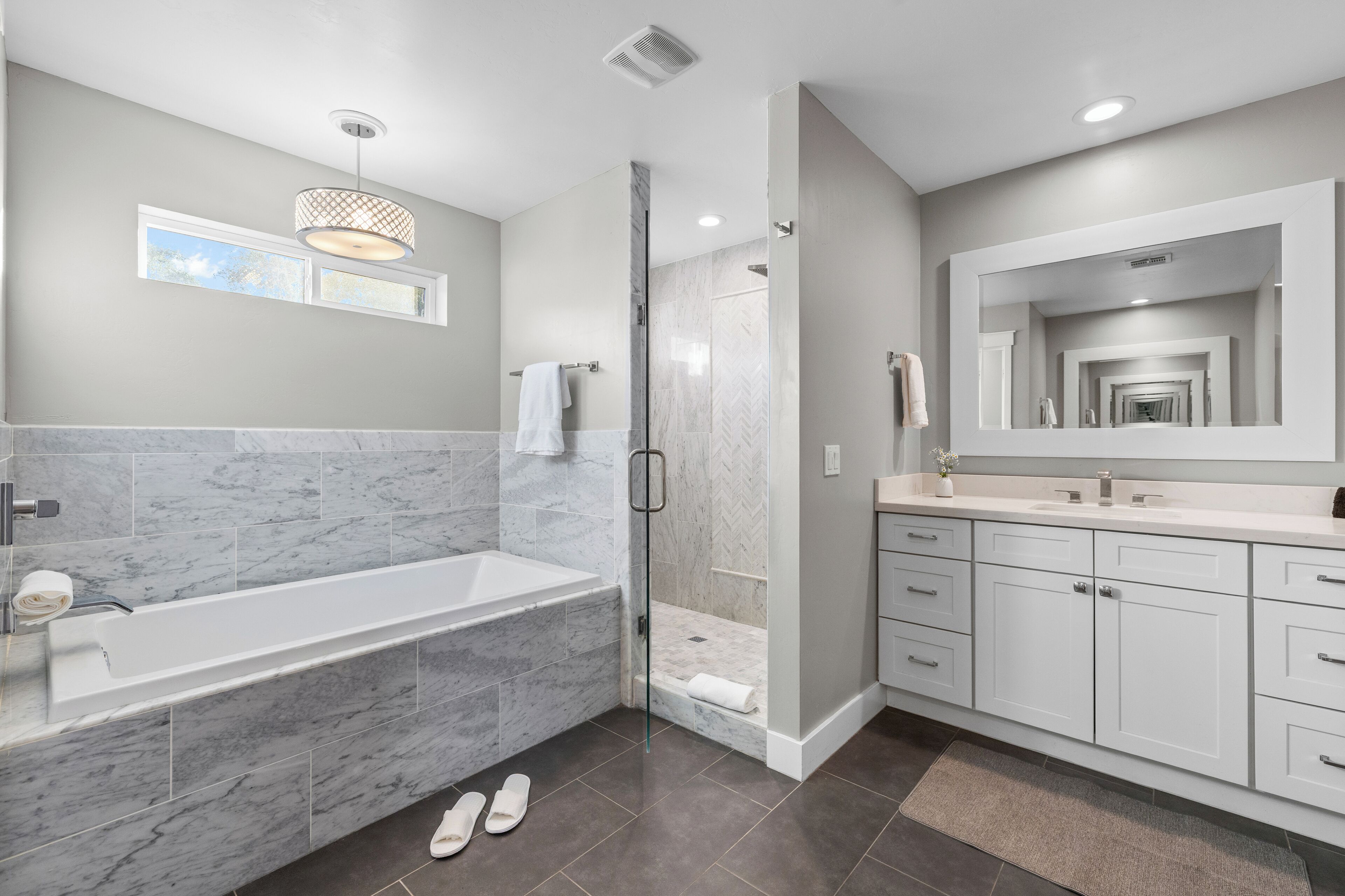 A modern bathroom with a large bathtub, a walk-in shower, and a vanity with a mirror.