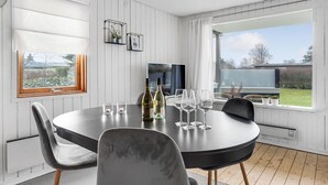 A dining area with a round table, chairs, wine bottles, glasses, and a view of the outdoors.