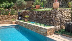 Ein Schwimmbecken mit Steinwänden und Topfpflanzen.