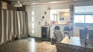 Ein geräumiger Wohnbereich mit Esstisch, Stühlen, einer Couch und einer Küche im Hintergrund.