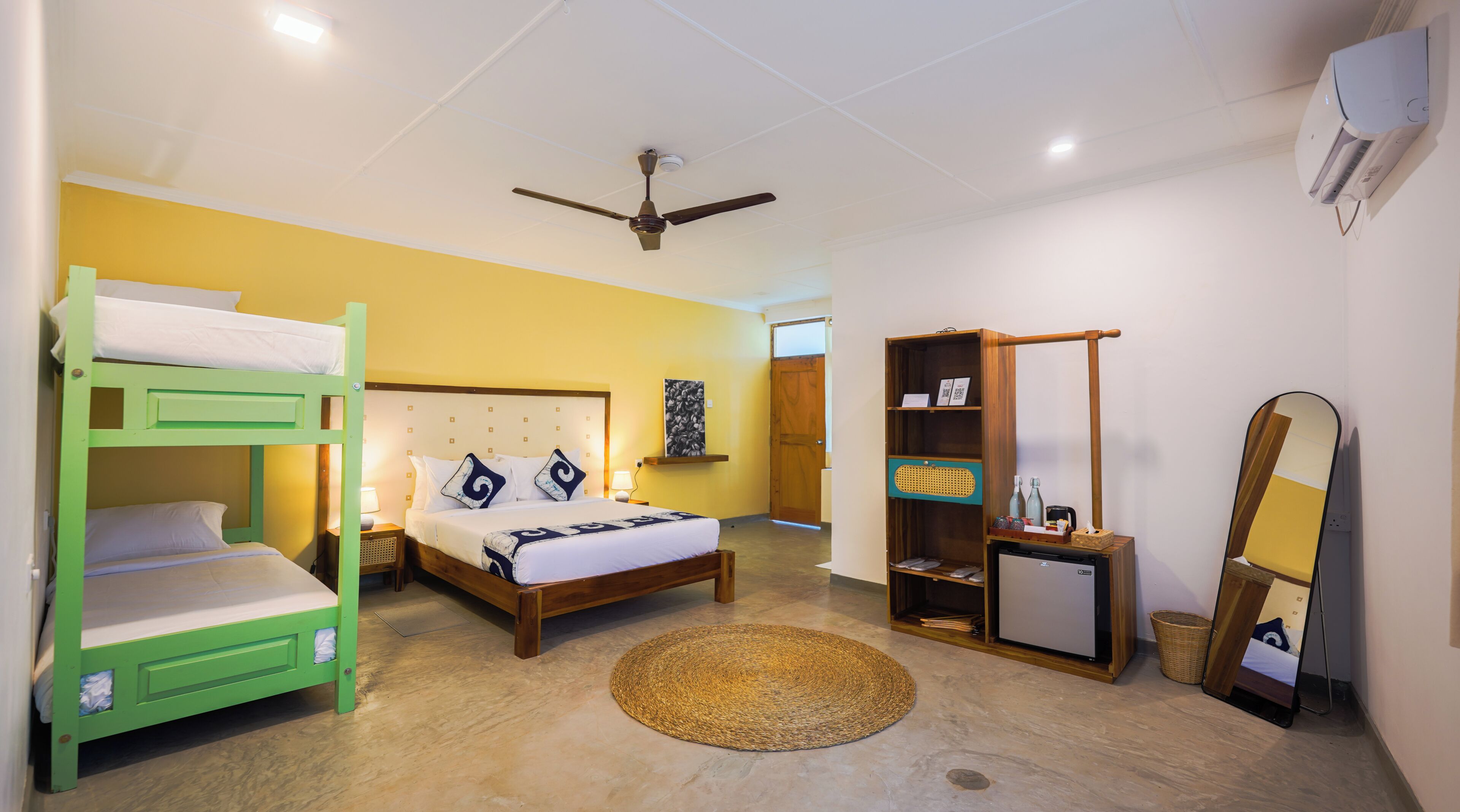 A room with bunk beds, a bed, a desk, a mirror, and a ceiling fan.