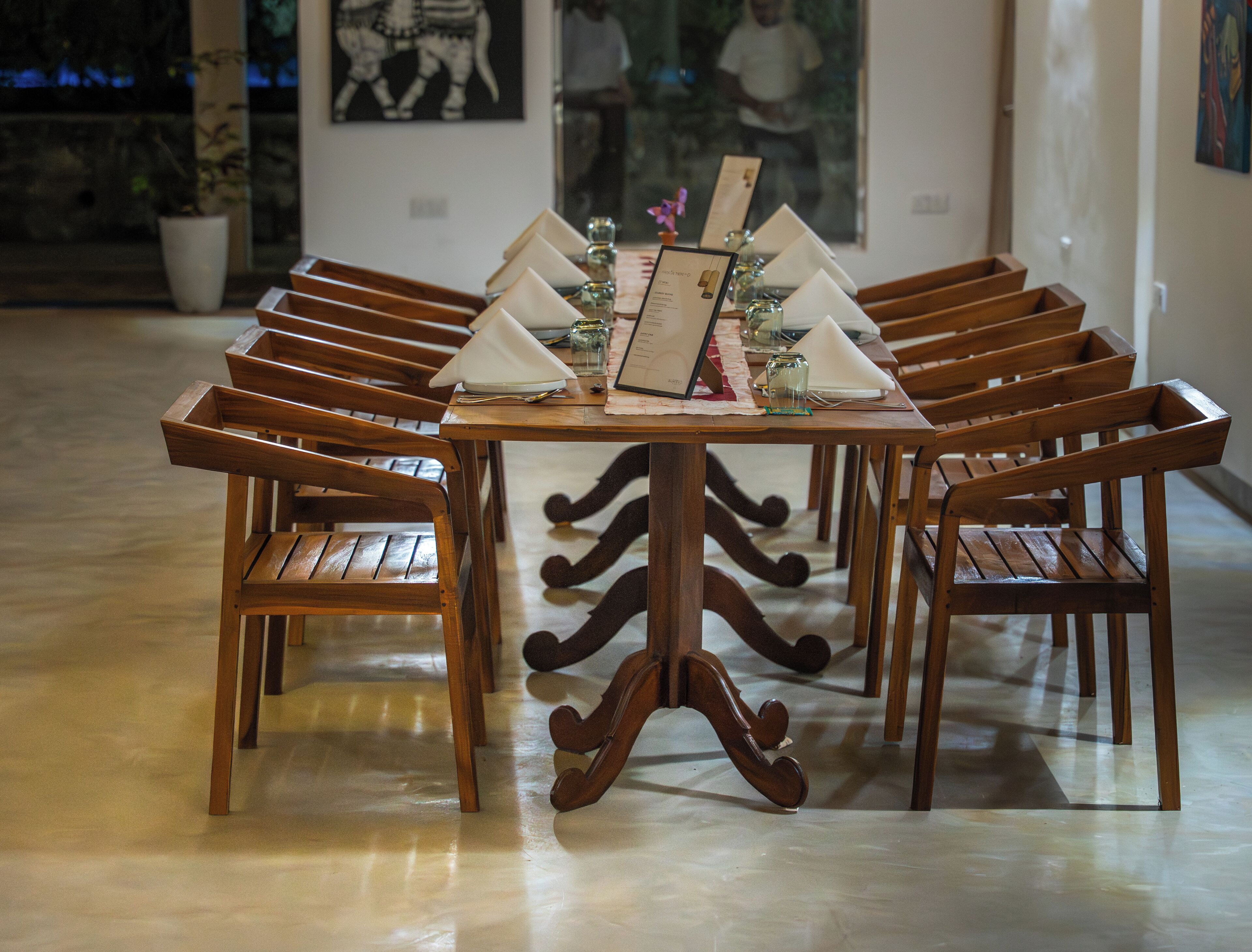 A dining table with wooden chairs, a menu, and a glass of water.