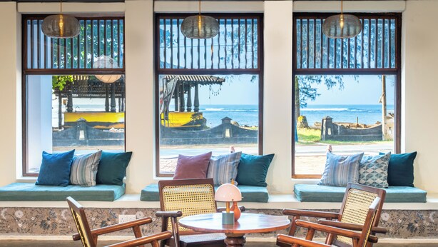 A seating area with a view of the ocean, featuring a round table and wooden chairs. - Surfing Elephant Resort (Polhena, Matara)