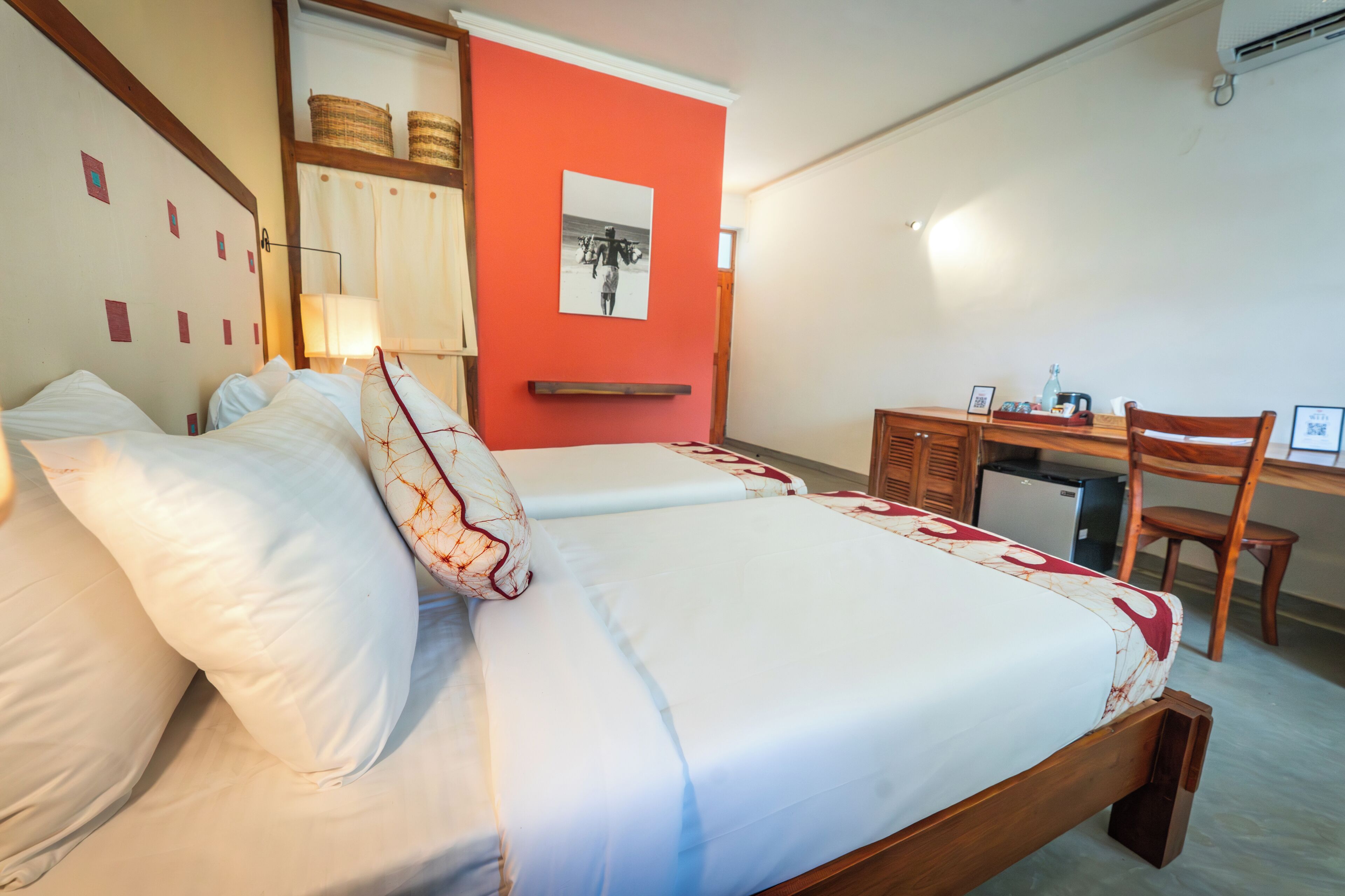 Una habitación de hotel con cama, escritorio, silla y un refrigerador pequeño.