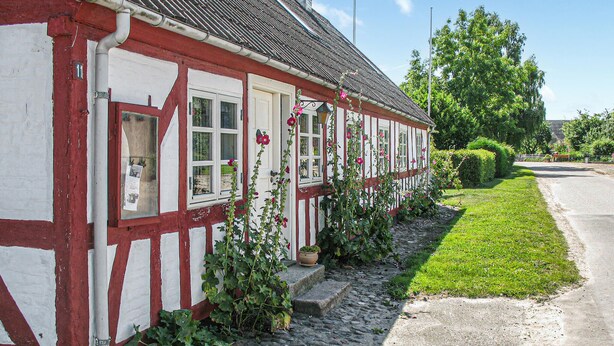 Ein traditionelles Fachwerkhäuschen mit einem Steinweg, der zum Eingang führt, umgeben von gepflegter Bepflanzung.