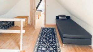 Ein kleiner, gemütlicher Raum mit Holzboden, einer dunklen Couch, einem kleinen Tisch und einem gemusterten Teppich.