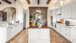 A spacious kitchen with white cabinetry, a large island, and a chandelier. - 5BDR Oasis w/ Waterfall Pool, Hot Tub, Desert View | Desert Cascase by AvantStay (Carefree)