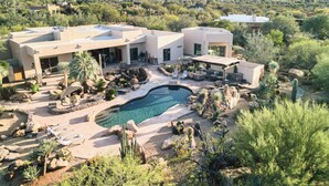A modern house with a pool surrounded by desert vegetation. - 5BDR Oasis w/ Waterfall Pool, Hot Tub, Desert View | Desert Cascase by AvantStay (Carefree)