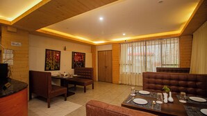 Comedor con techo de madera, mesa para cuatro personas dispuesta y un amplio ventanal con cortinas.