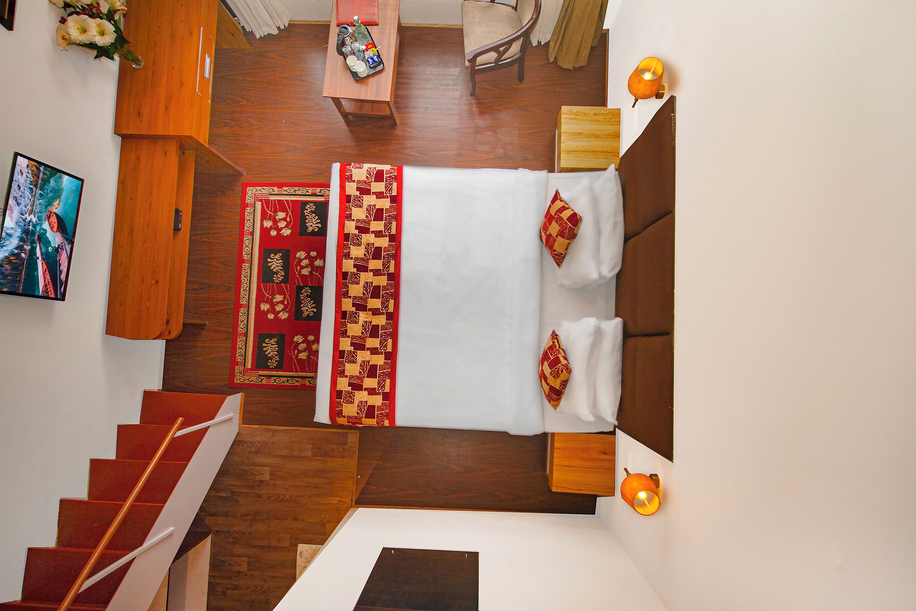 Una habitación de hotel con una cama, un escritorio, una silla, una mesita y una escalera.
