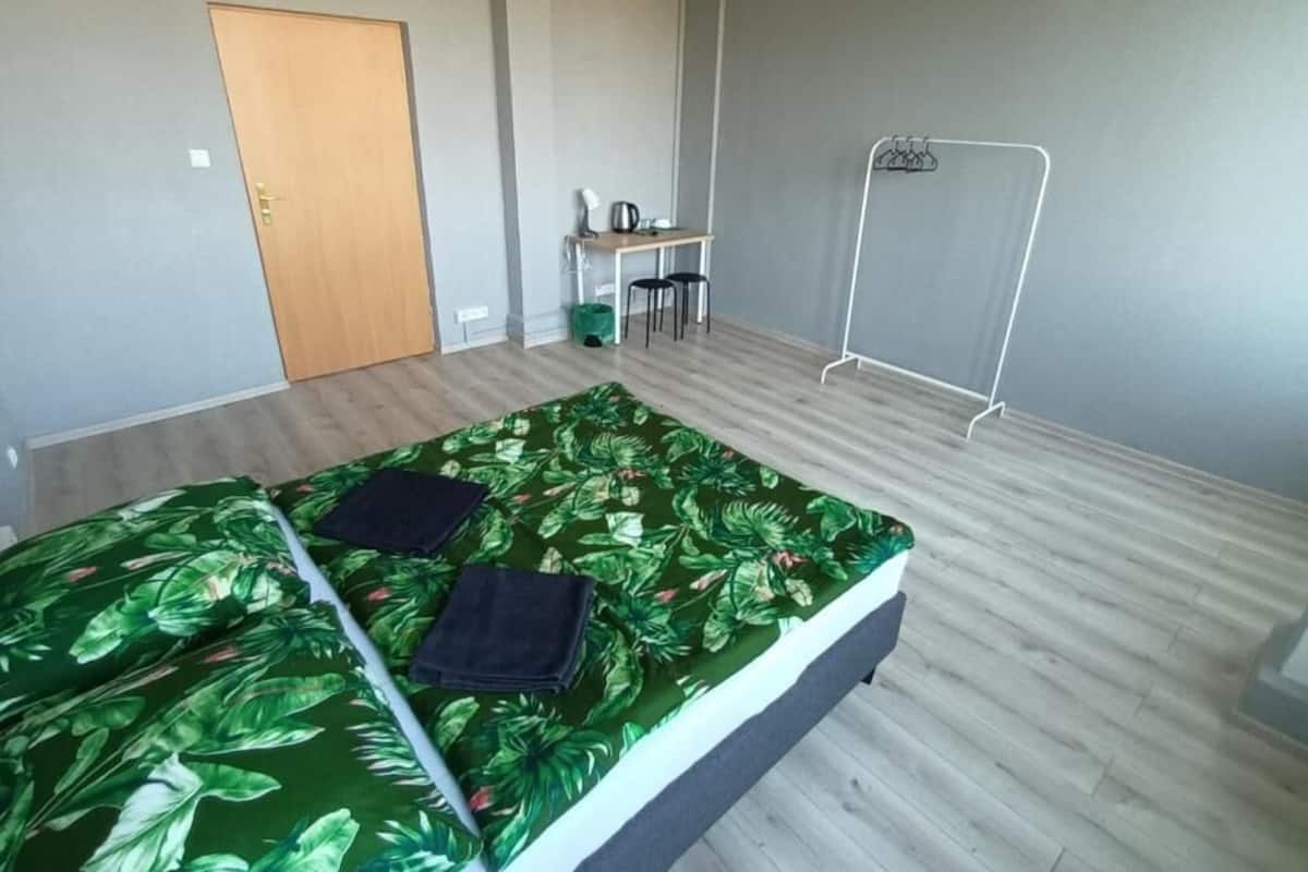 Ein Zimmer mit Bett, Schreibtisch, Stuhl und Kleiderhaken.