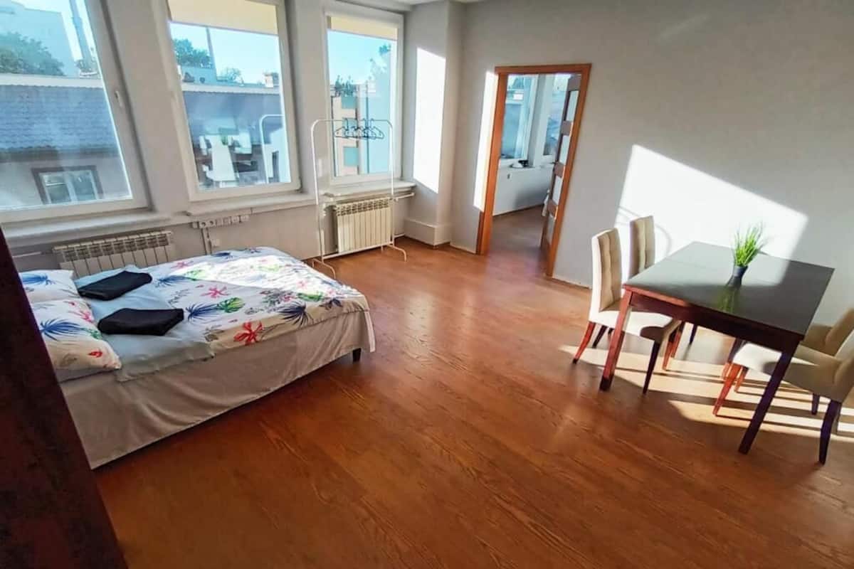 Ein Schlafzimmer mit einem Bett, einem kleinen Tisch, einem Stuhl und einer Heizung.