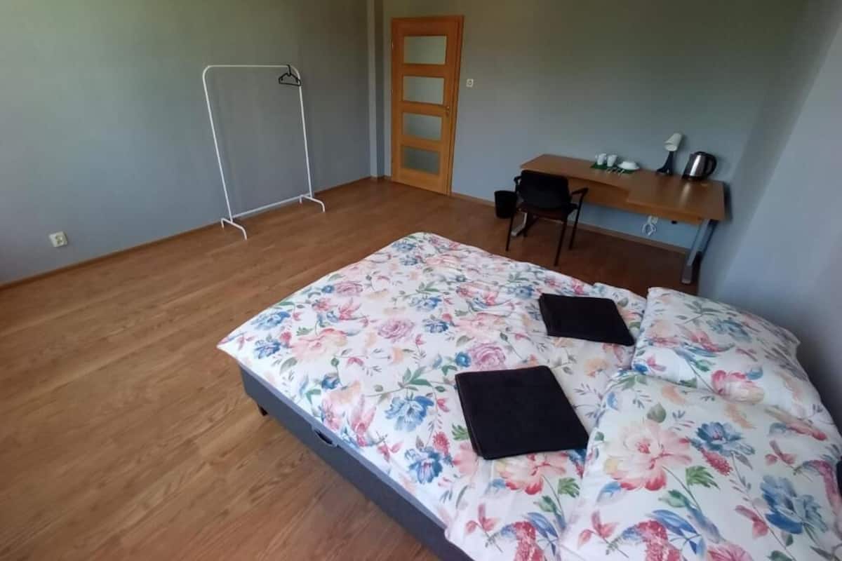 Ein Zimmer mit einem Bett, einem Holztisch, einem Stuhl und einer Tür.
