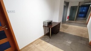 Un pasillo con una puerta que indica 211-212, un escritorio pequeño con una computadora y un suelo de baldosas.