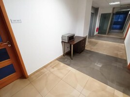 Un pasillo con una puerta que indica 211-212, un escritorio pequeño con una computadora y un suelo de baldosas.