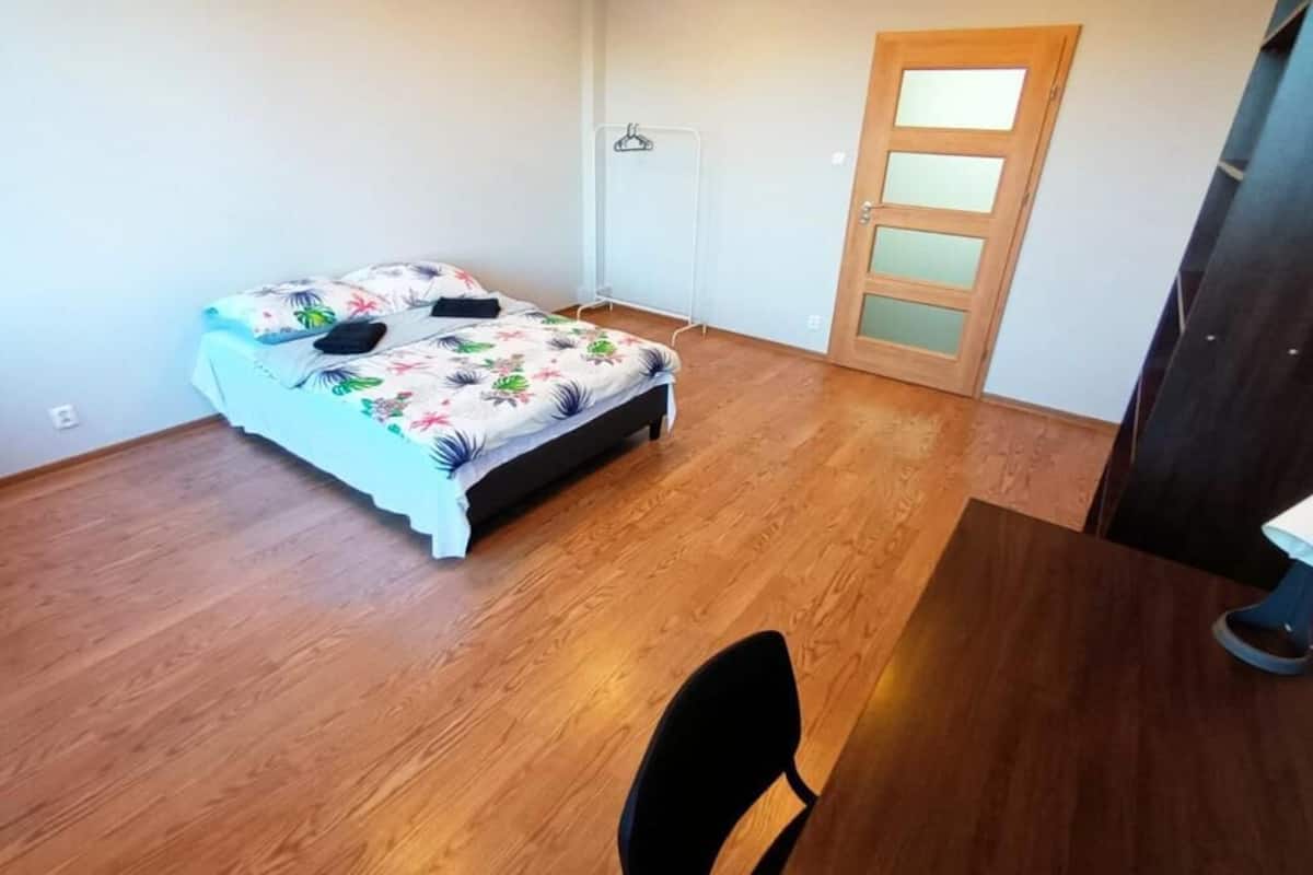Ein Schlafzimmer mit Bett, Holzboden, Stuhl und Tür.