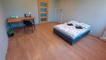 Un dormitorio con cama, escritorio, silla y armario.
