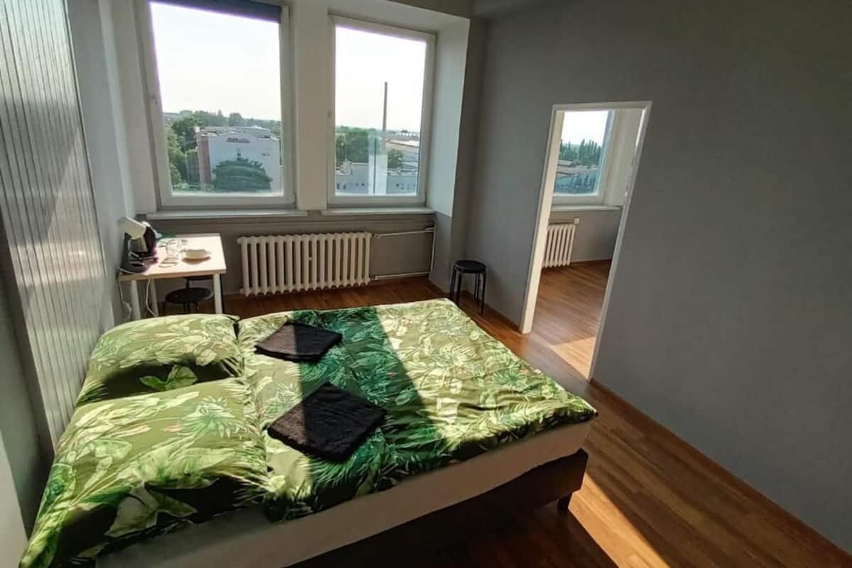 Ein Schlafzimmer mit Bett, Schreibtisch und Blick durch eine offene Tür.