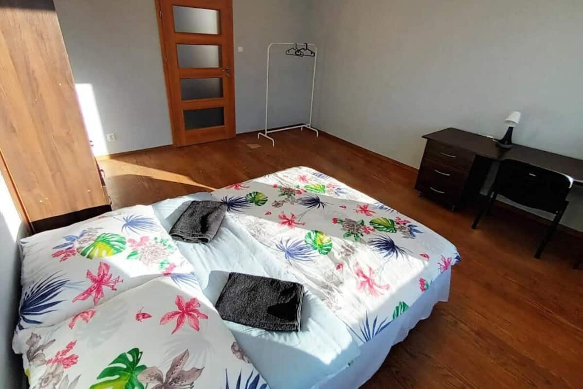 Ein Schlafzimmer mit Bett, Holzboden, Kleiderschrank, Schreibtisch und einer Tür.