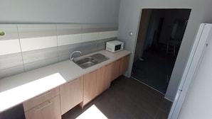 Una cocina moderna con encimera blanca, pileta de acero inoxidable y armarios de madera.