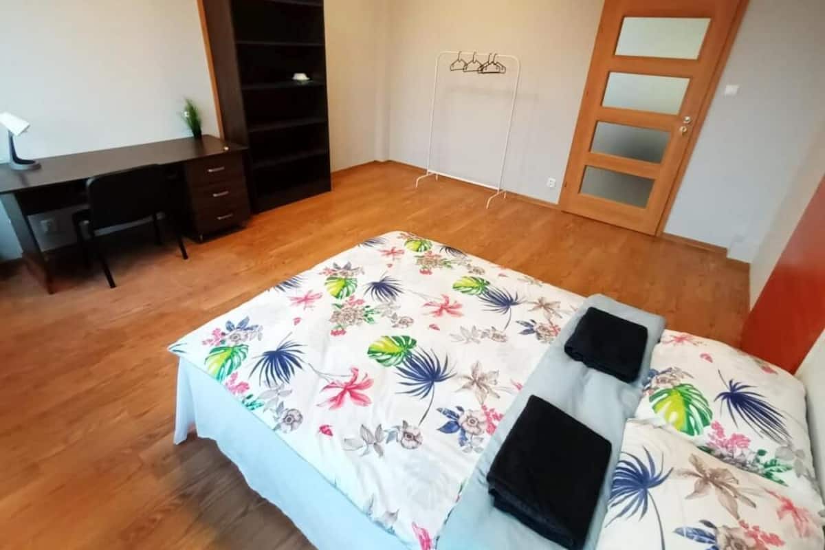Ein Schlafzimmer mit Bett, Schreibtisch, Kleiderschrank und einer Tür.