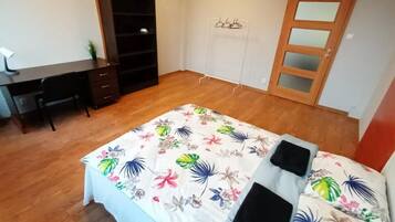 Un dormitori amb llit, escriptori, armari i porta.
