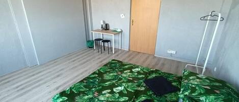 Um quarto com uma cama, uma escrivaninha e uma porta.