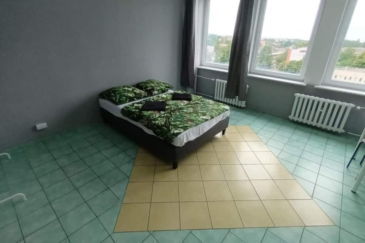 Ein Schlafzimmer mit einem Bett, einem Heizkörper und einem Fenster mit Vorhängen.