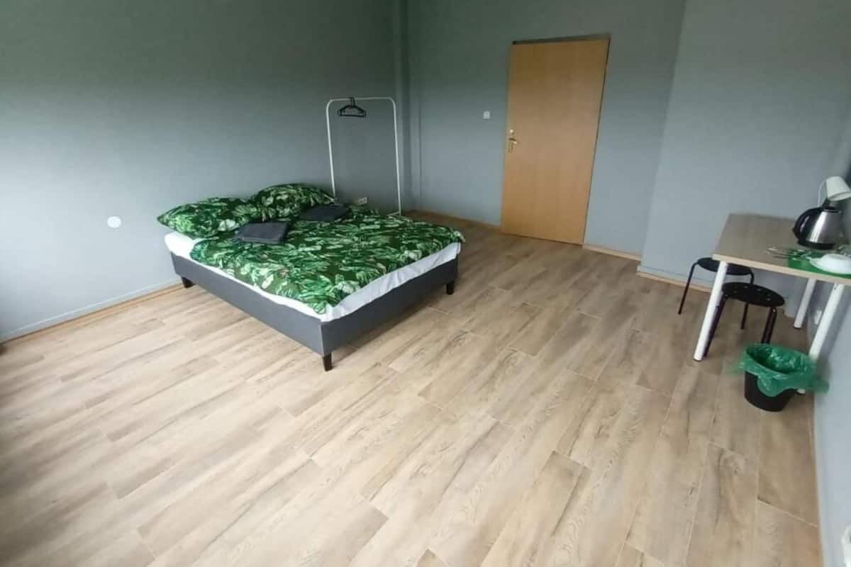 Ein Zimmer mit einem Bett, einem Schreibtisch, einem Stuhl und einer Tür.