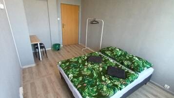 A small, neatly arranged room with a bed, a desk, and a chair.