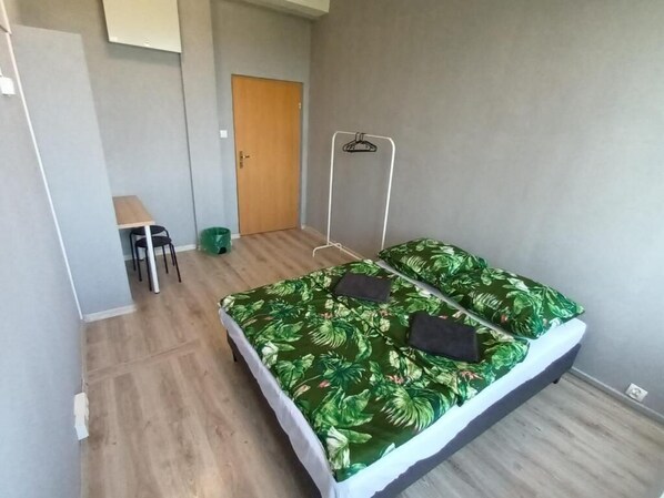 Een kleine, verzorgde kamer met een bed, een bureau en een stoel.